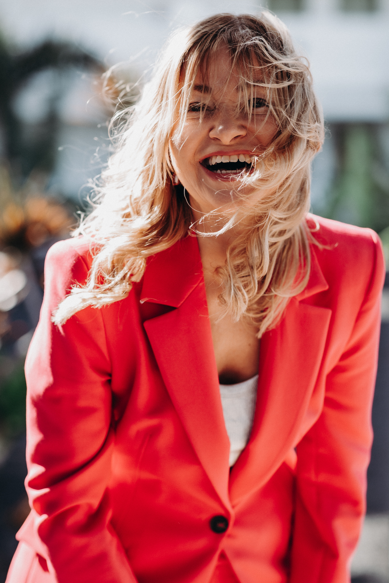 Claudia Homberg lacht, windverwehte Haare, roter Blazer